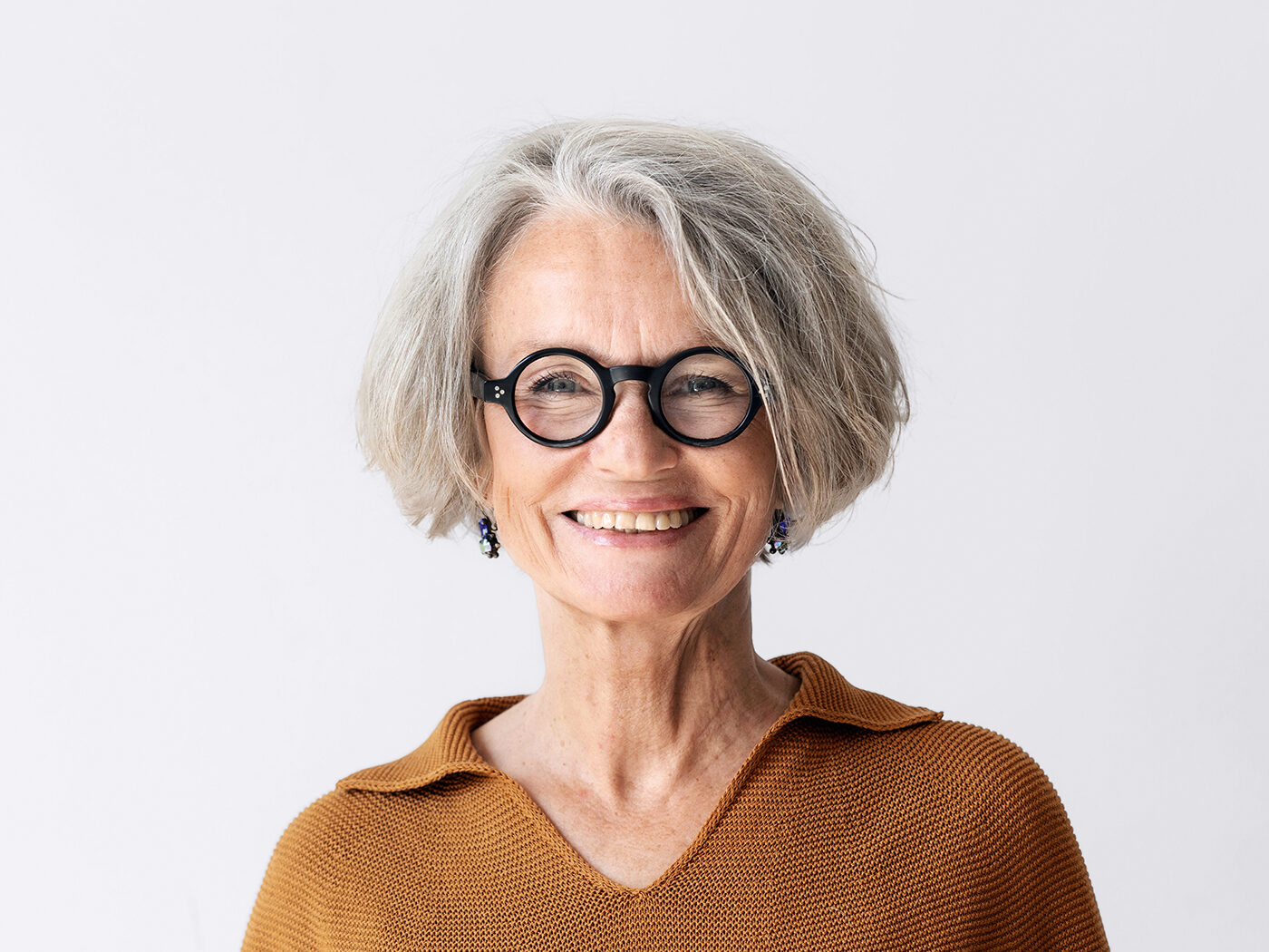 Porträt einer selbstbewussten Seniorin mit kurzen Haaren und Brille, die in ihrer Selbsthilfegruppe den Job einer Kamerafrau hat.