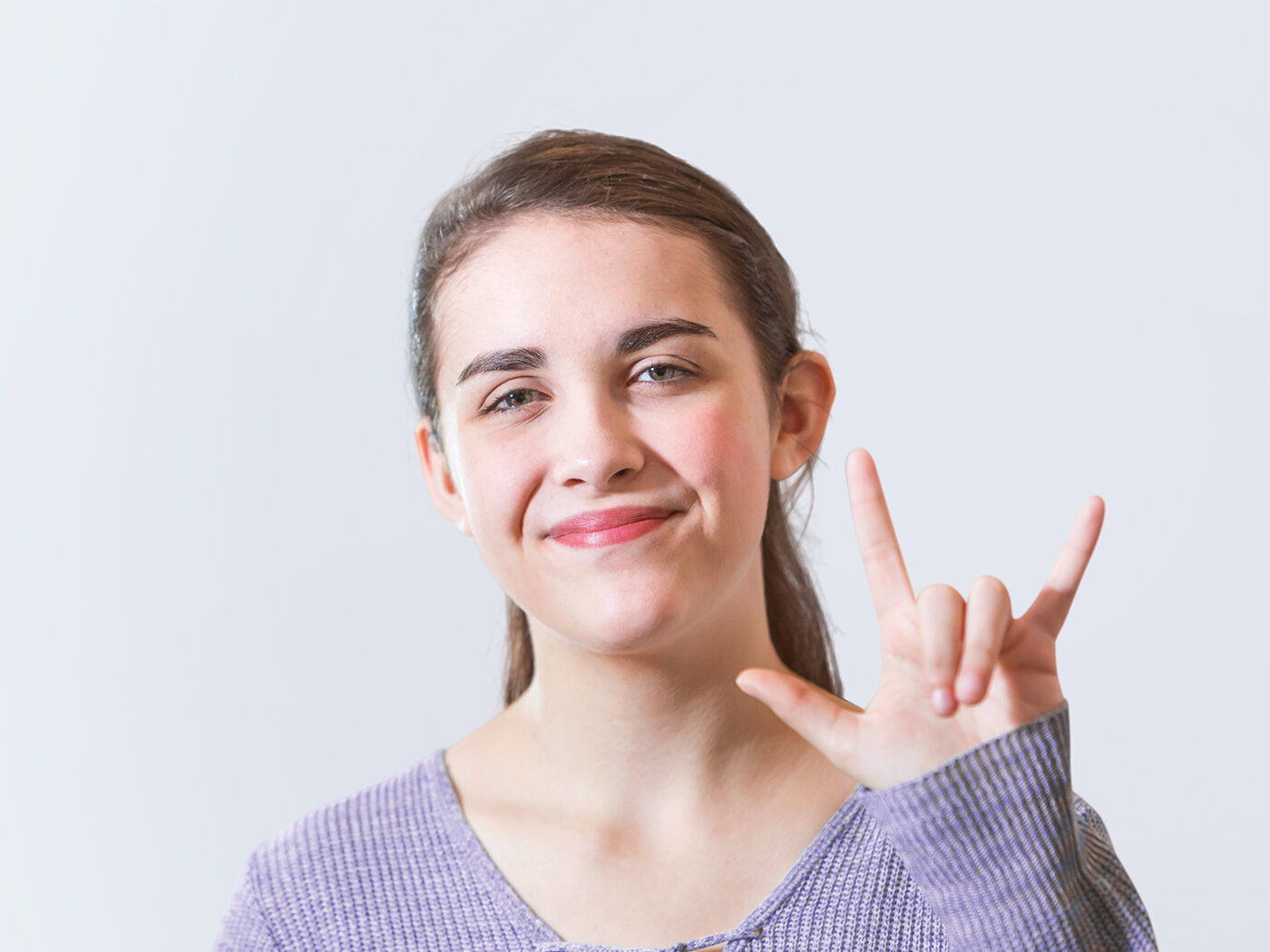 Portrait einer jungen gehörlosen Frau, die mit Gebärdensprache kommuniziert und die in ihrer Selbsthilfegruppe den Job eines Tourguide hat.